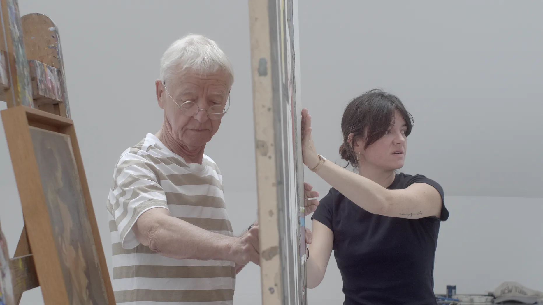 Daniel Authouart et sa fille manipulant ensemble une grande toile ou un cadre, dans le studio
