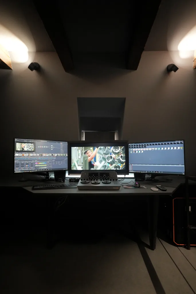 Studio de post-production et de montage vidéo équipé de trois moniteurs professionnels.
